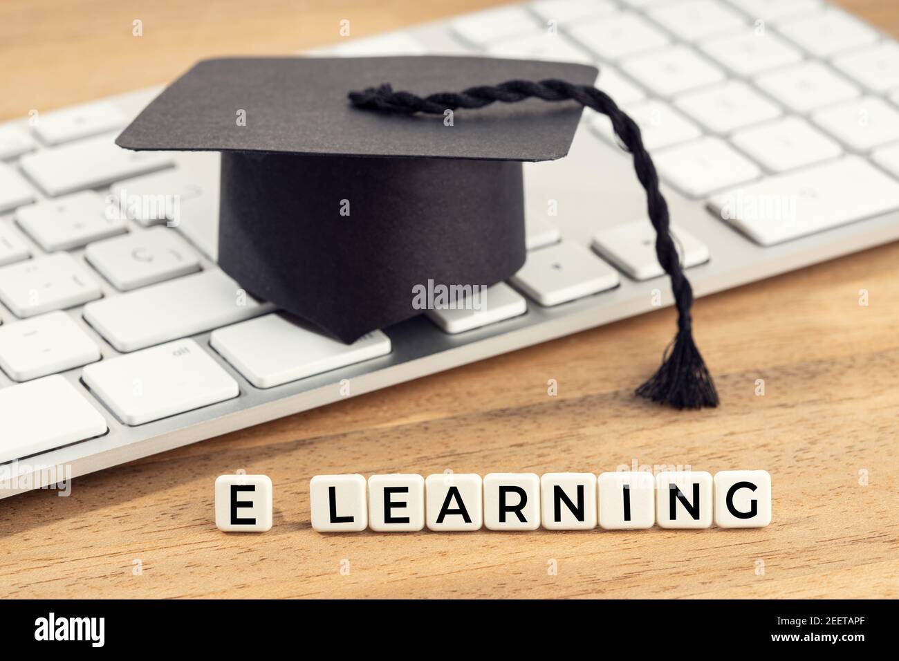 E-Learning o concepto de estudio en casa. Tapa de graduación en el teclado de la computadora en el escritorio de madera Foto de stock