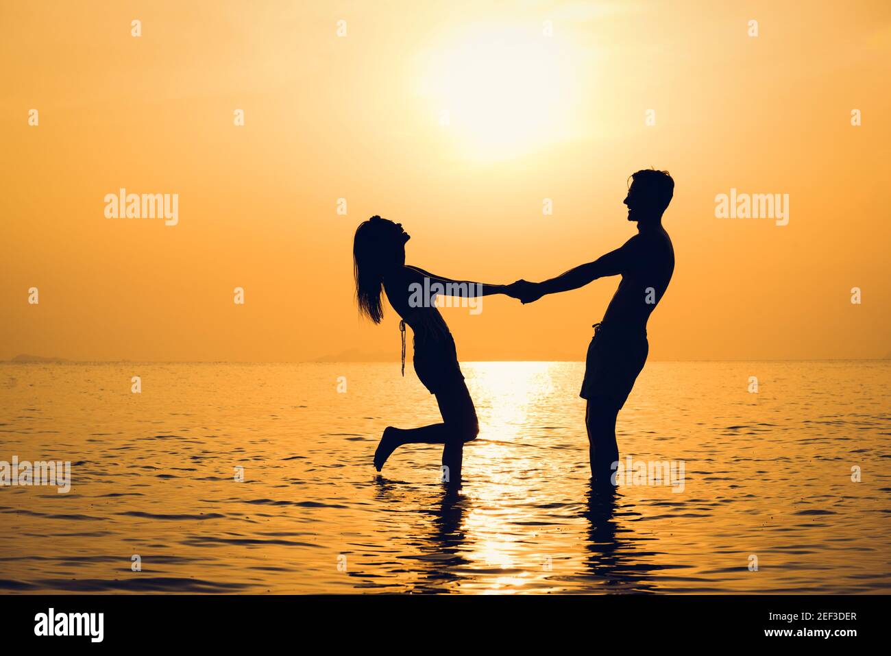 Silueta de feliz pareja de manos en la playa al atardecer Foto de stock
