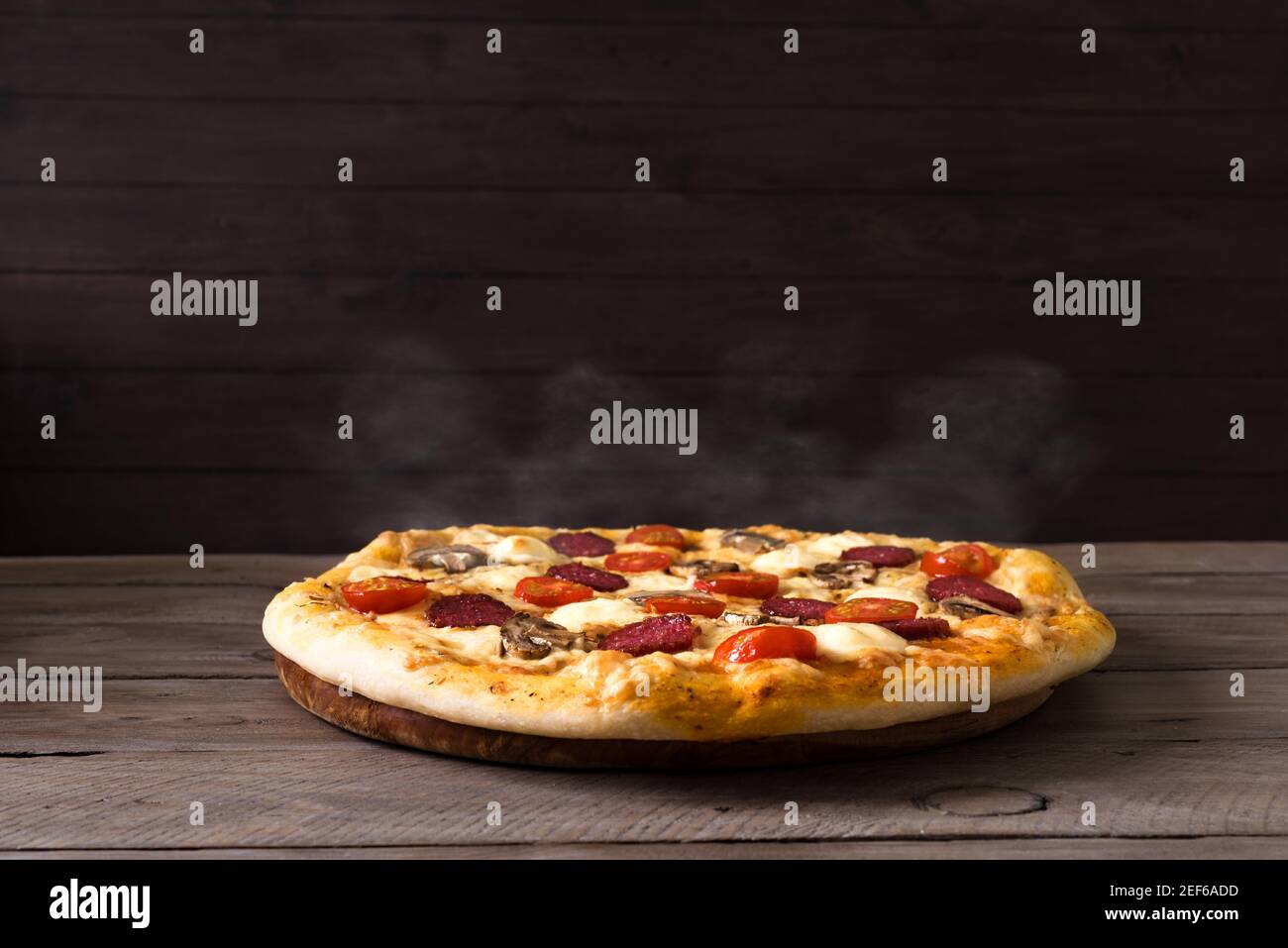 Pizza italiana tradicional con mozzarella y salami. Pizza caliente sólo de  horno, fondo negro, espacio de copia. Entrega de pizza o pizzería promoción  c Fotografía de stock - Alamy