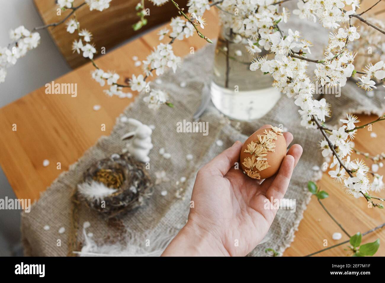 La mano que sostiene el huevo de Pascua decorado con pétalos de