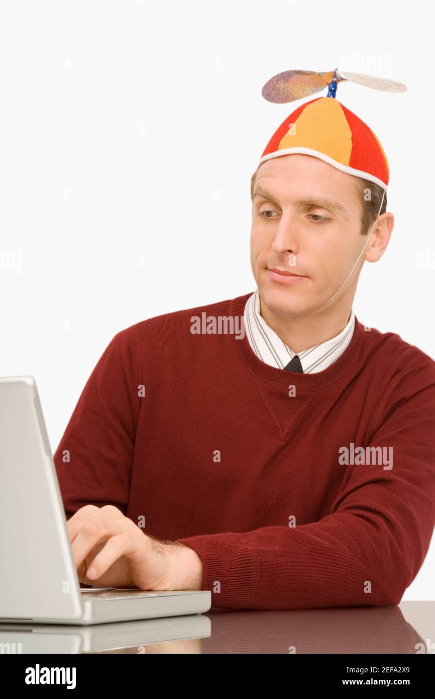 Hombre de negocios con un gorro de hélice y trabajando en un portátil  Fotografía de stock - Alamy