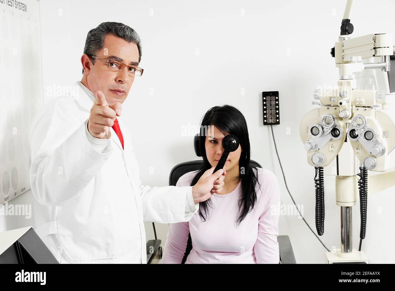 Retrato de un médico masculino que examina un ojo womanÅ½s joven Foto de stock