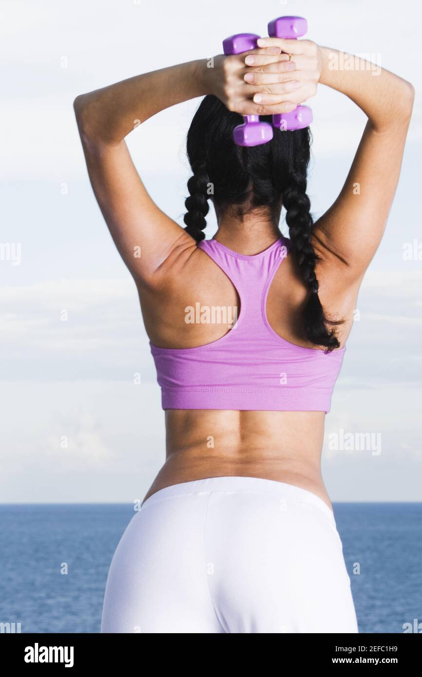 Vista trasera de una mujer joven el ejercicio con pesas Foto de stock