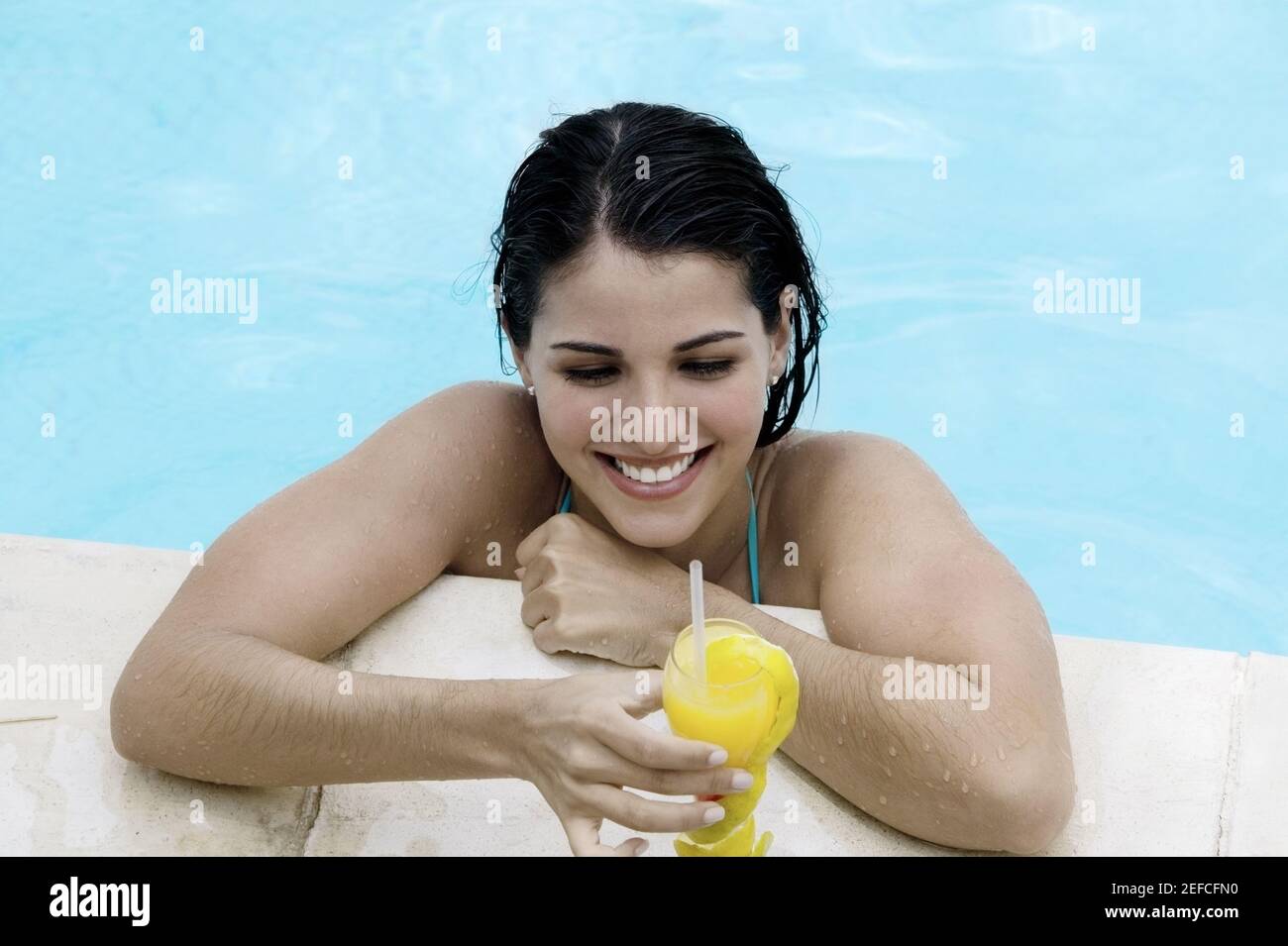 Vista en ángulo alto de una joven que toma una bebida en una piscina Foto de stock