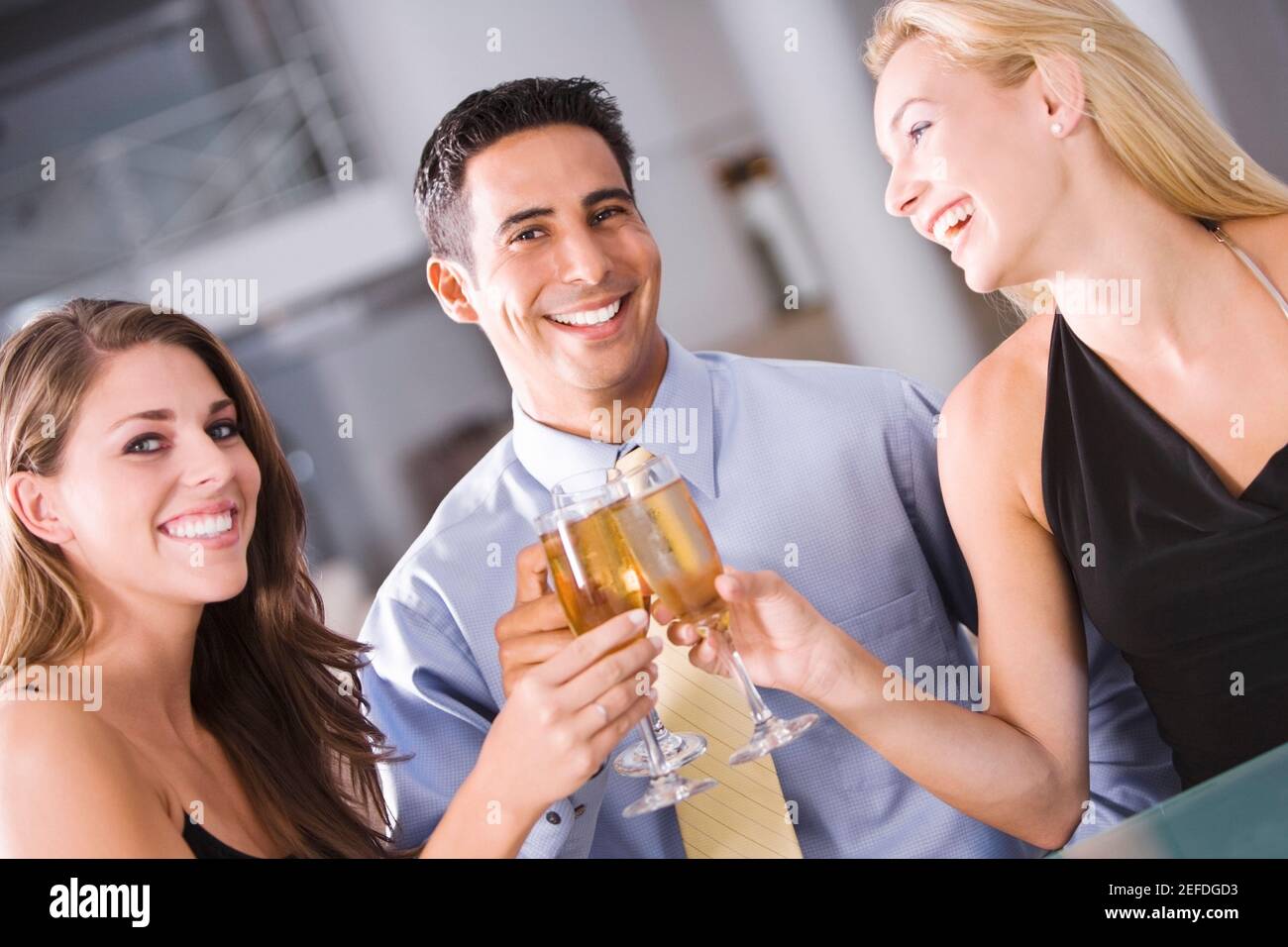 Retrato de un hombre adulto medio levantando una tostada con dos mujeres jóvenes Foto de stock