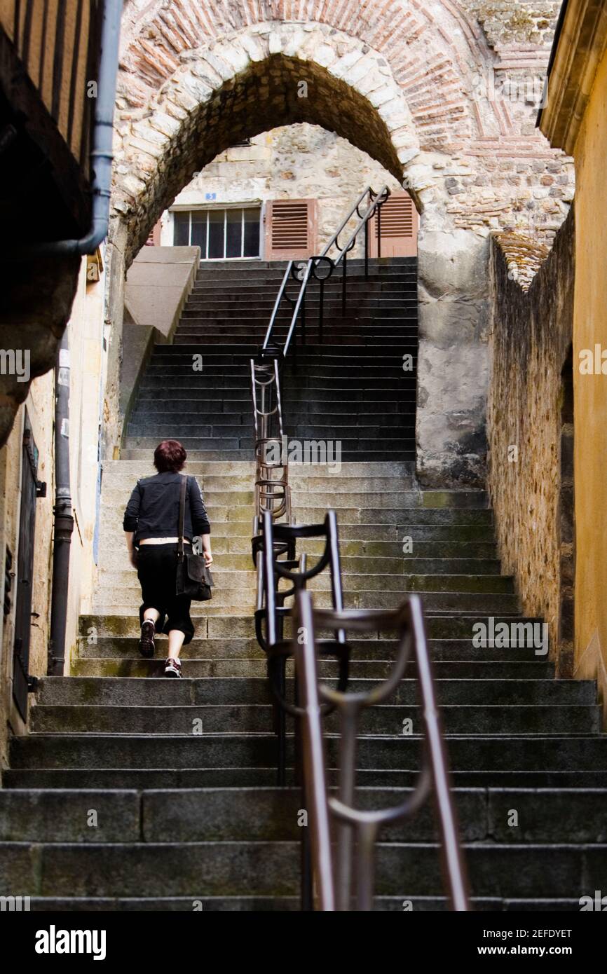 Vista trasera de una mujer subiendo por la escalera, Escalier de la Grande Poterne, le Mans, Sarthe, Francia Foto de stock