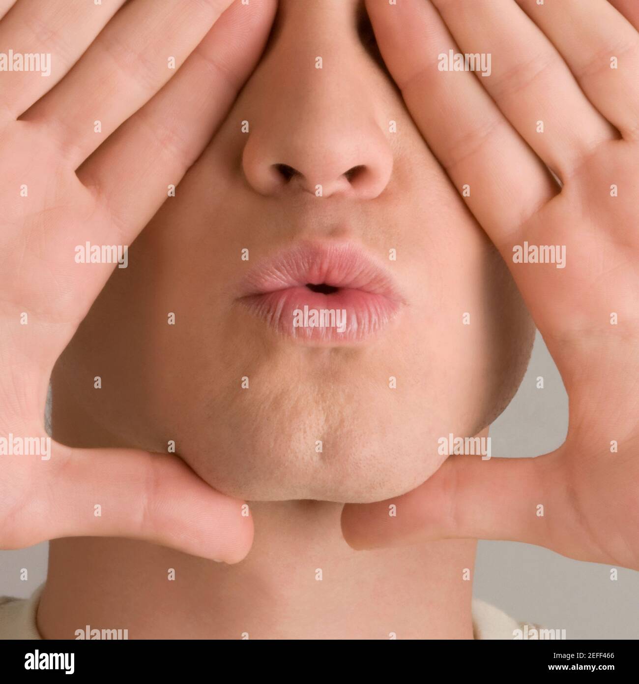 Primer plano de un joven que cubre sus ojos con los suyos manos Foto de stock
