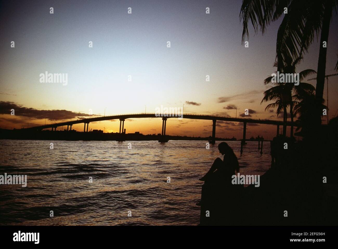Tranquilo paisaje marino y un puente que se perfila contra el cielo al atardecer, Grand Bahamas, Bahamas Foto de stock