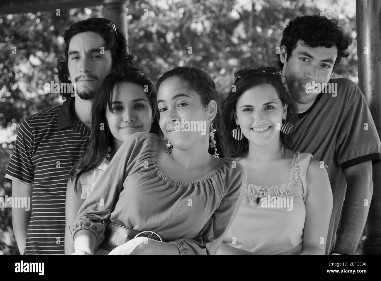 Retrato de tres jóvenes mujeres de pie con sus amigos Foto de stock