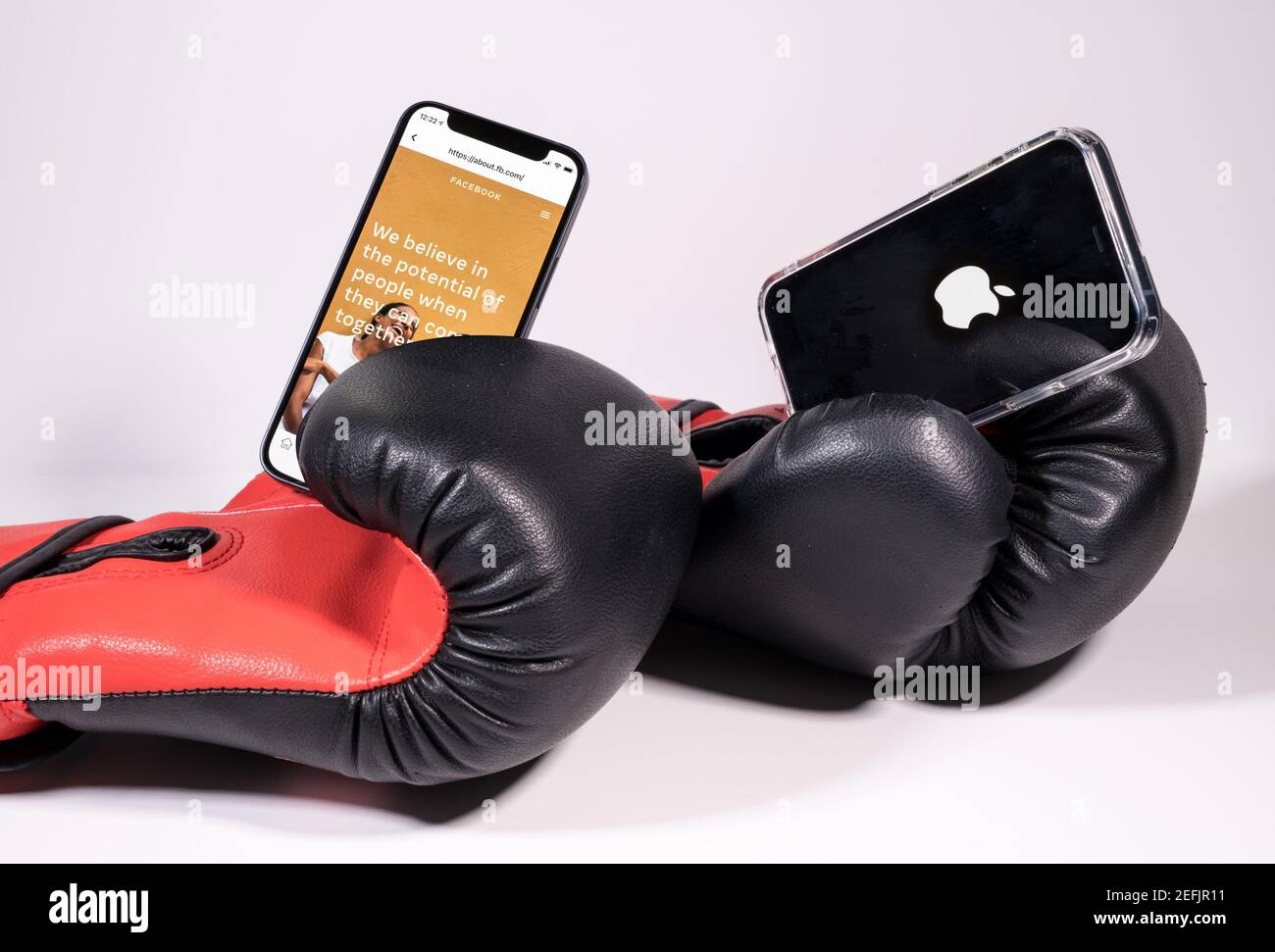 Morgantown, WV - 17 de febrero de 2021: Símbolo de manzana en iphone y Facebook en guantes de boxeo para ilustrar la controversia de privacidad Foto de stock