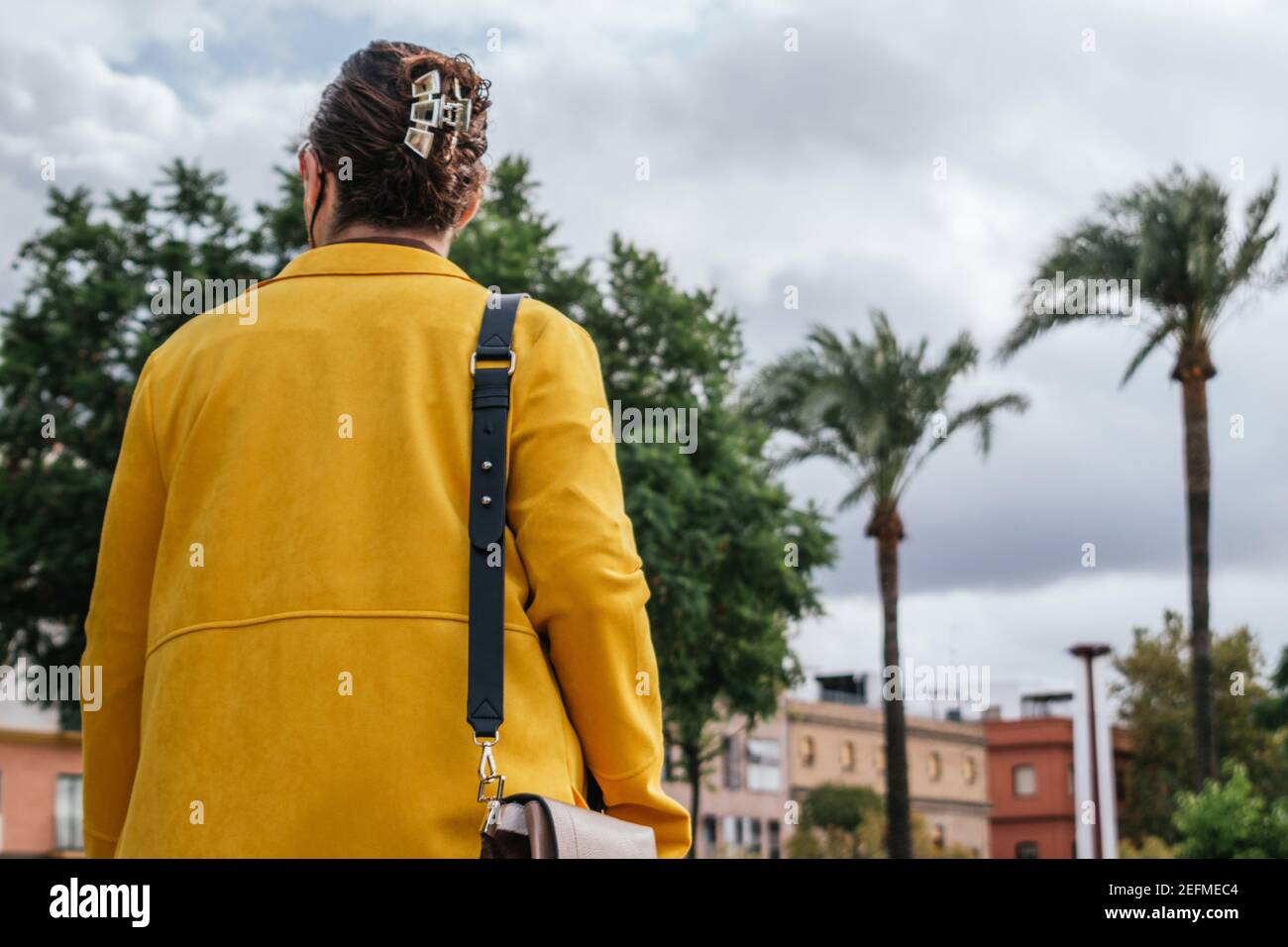 Mujer en un abrigo amarillo con la espalda girada calle Foto de stock