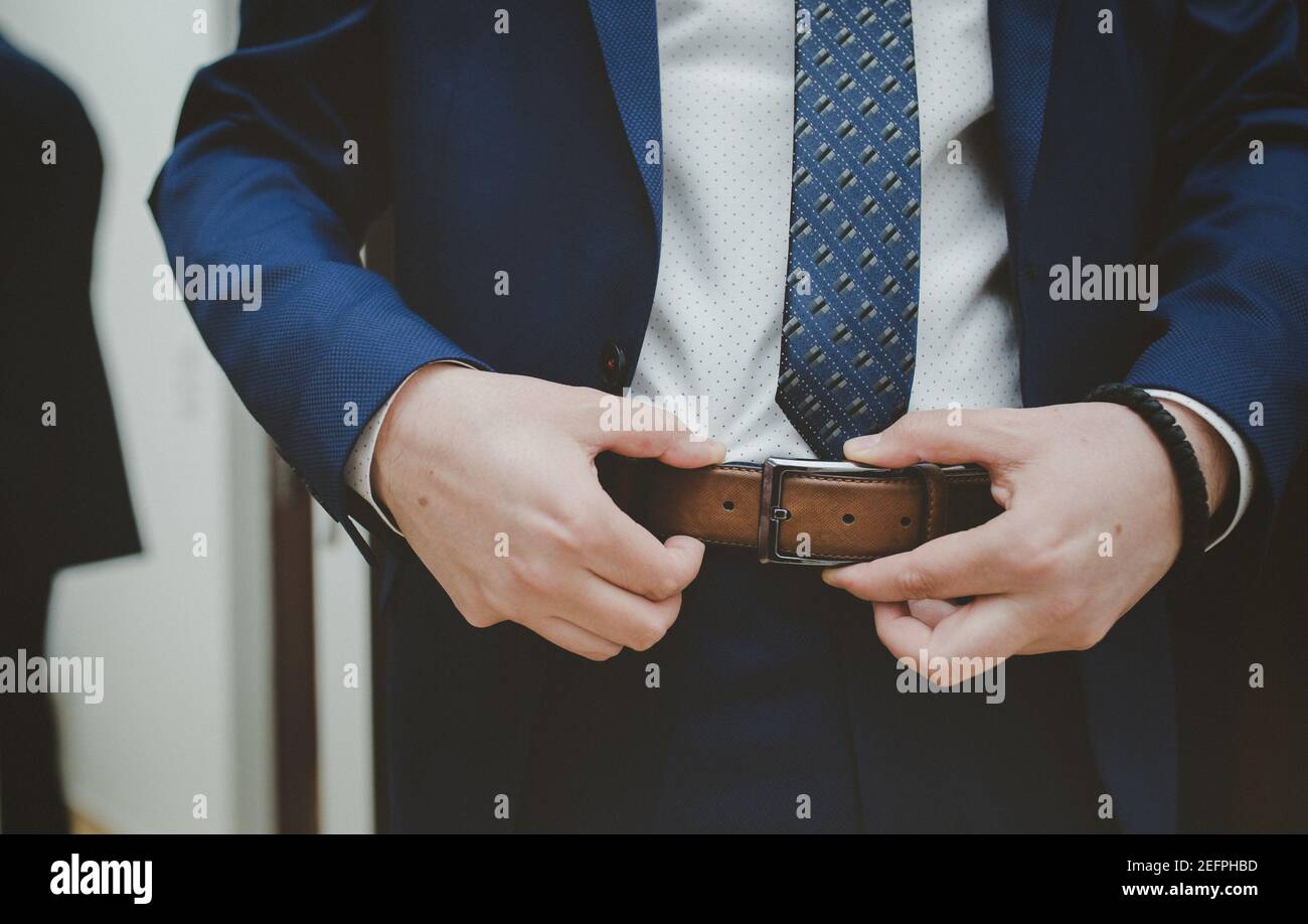 Primer plano de un hombre elegante en un traje azul de ajuste el cinturón  de cuero en h Fotografía de stock - Alamy