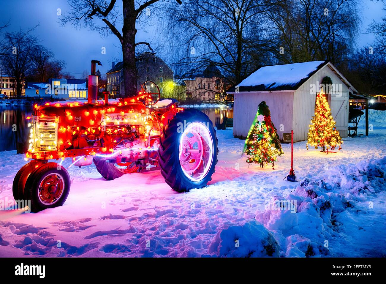 Tractor ornamentado e iluminado y árboles de Christmass en el patio, Red Mill Museum Village, Clinton, Hunterdon County, Nueva Jersey Foto de stock