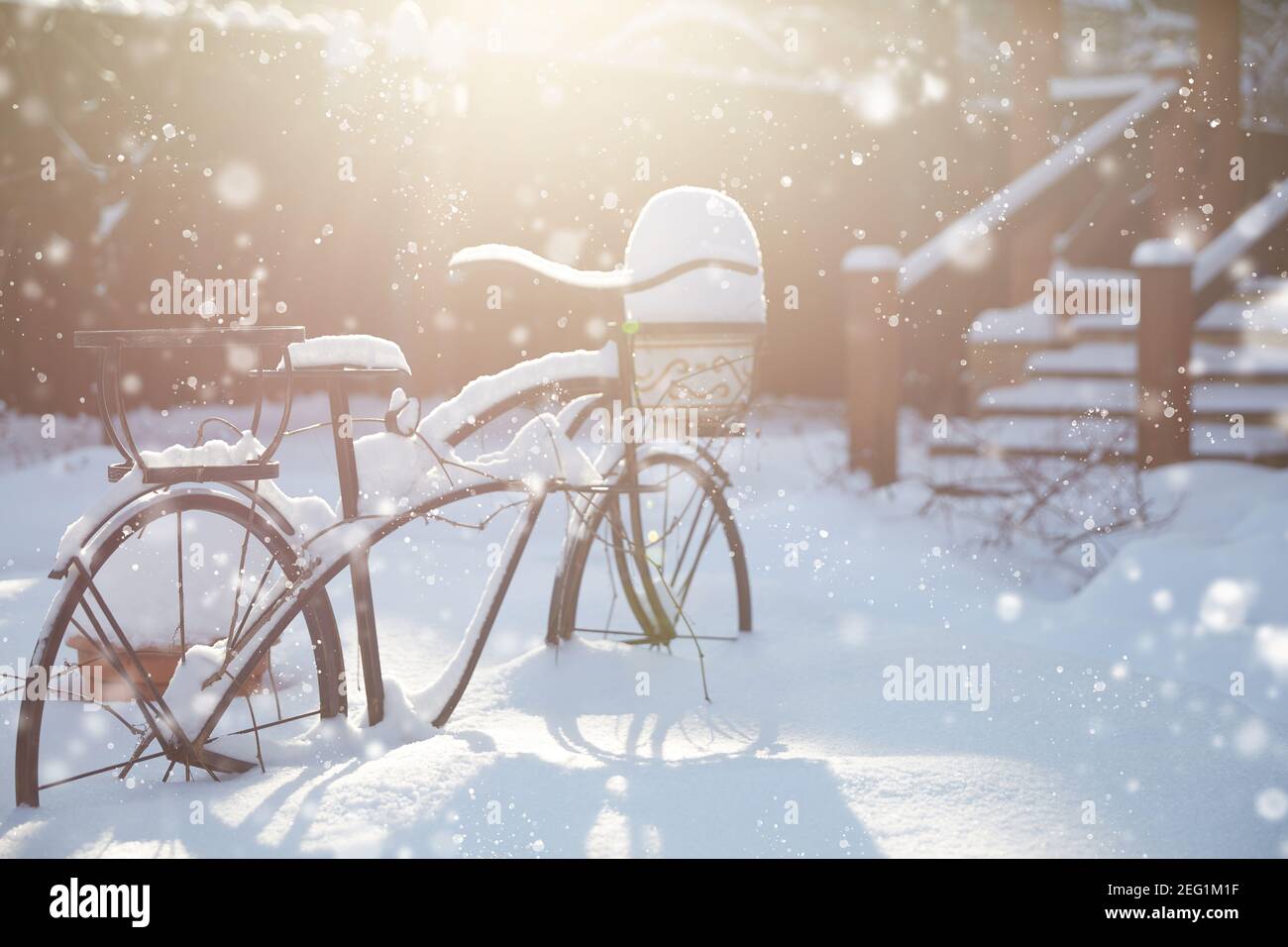 Decoración de jardín en la temporada de invierno bajo la nieve blanca. Jardín de pie para macetas de flores en forma de bicicleta en la nieve. Luz de contorno con sol Foto de stock