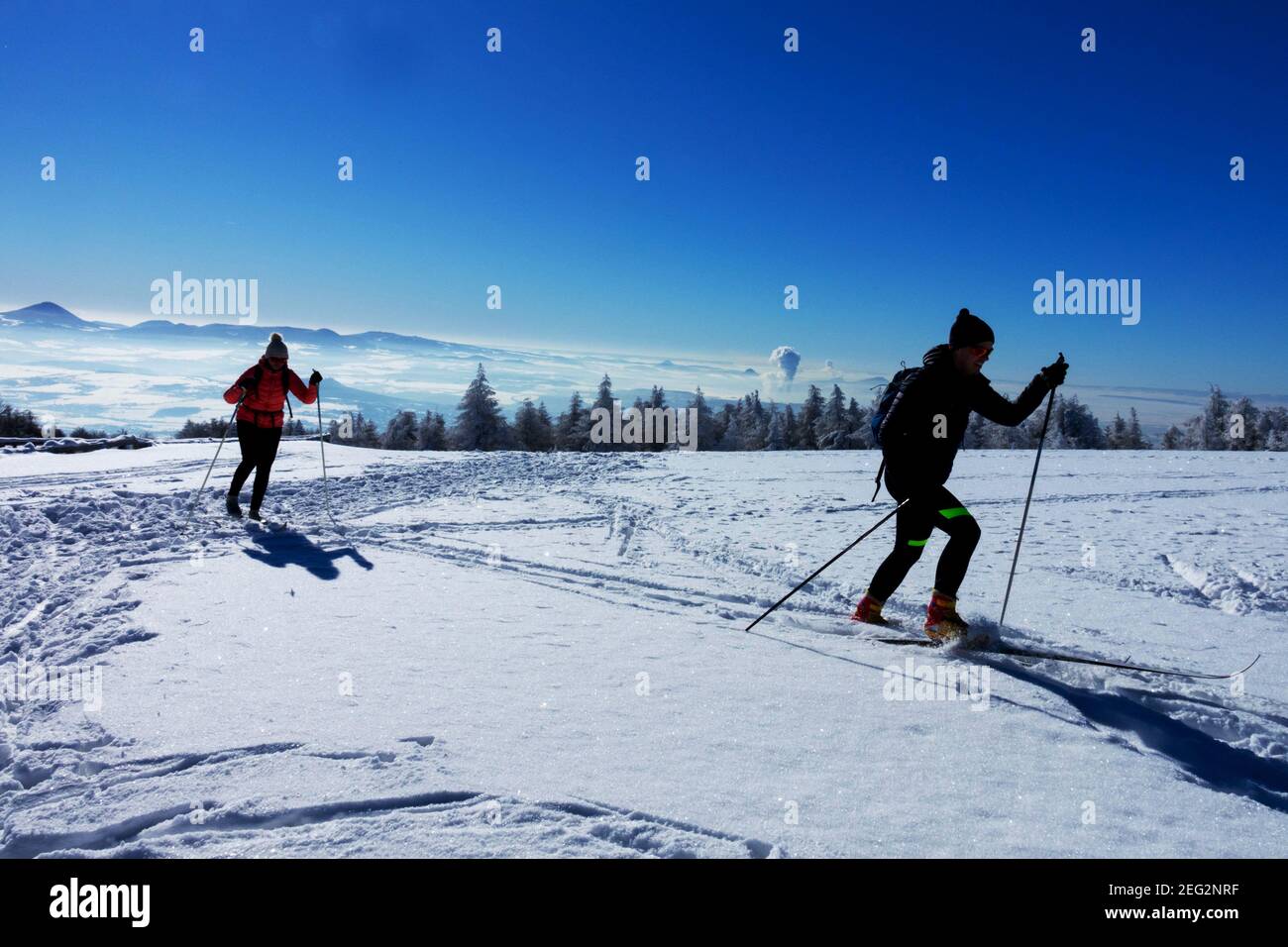 Siluetas de un par de esquiadores disfrutando de un sol agradable día en un paisaje nevado Foto de stock