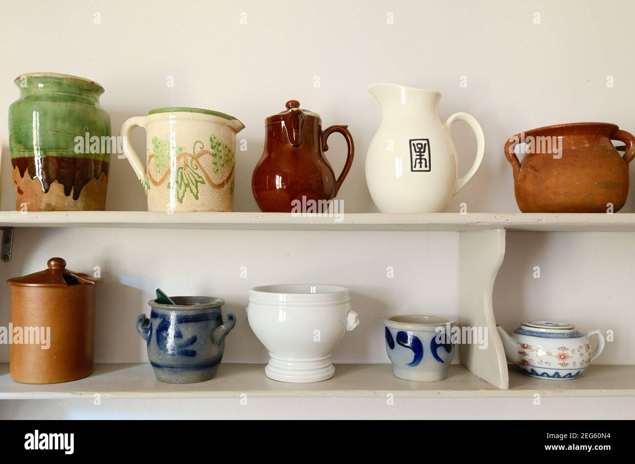 Estantes blancos de madera con exhibición o colección de ollas de cerámica, cerámica y cuencos Foto de stock