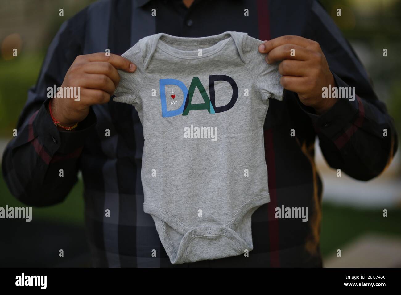 Futuro padre sosteniendo ropa de bebé con amo a mi papá imprimir Fotografía de stock - Alamy