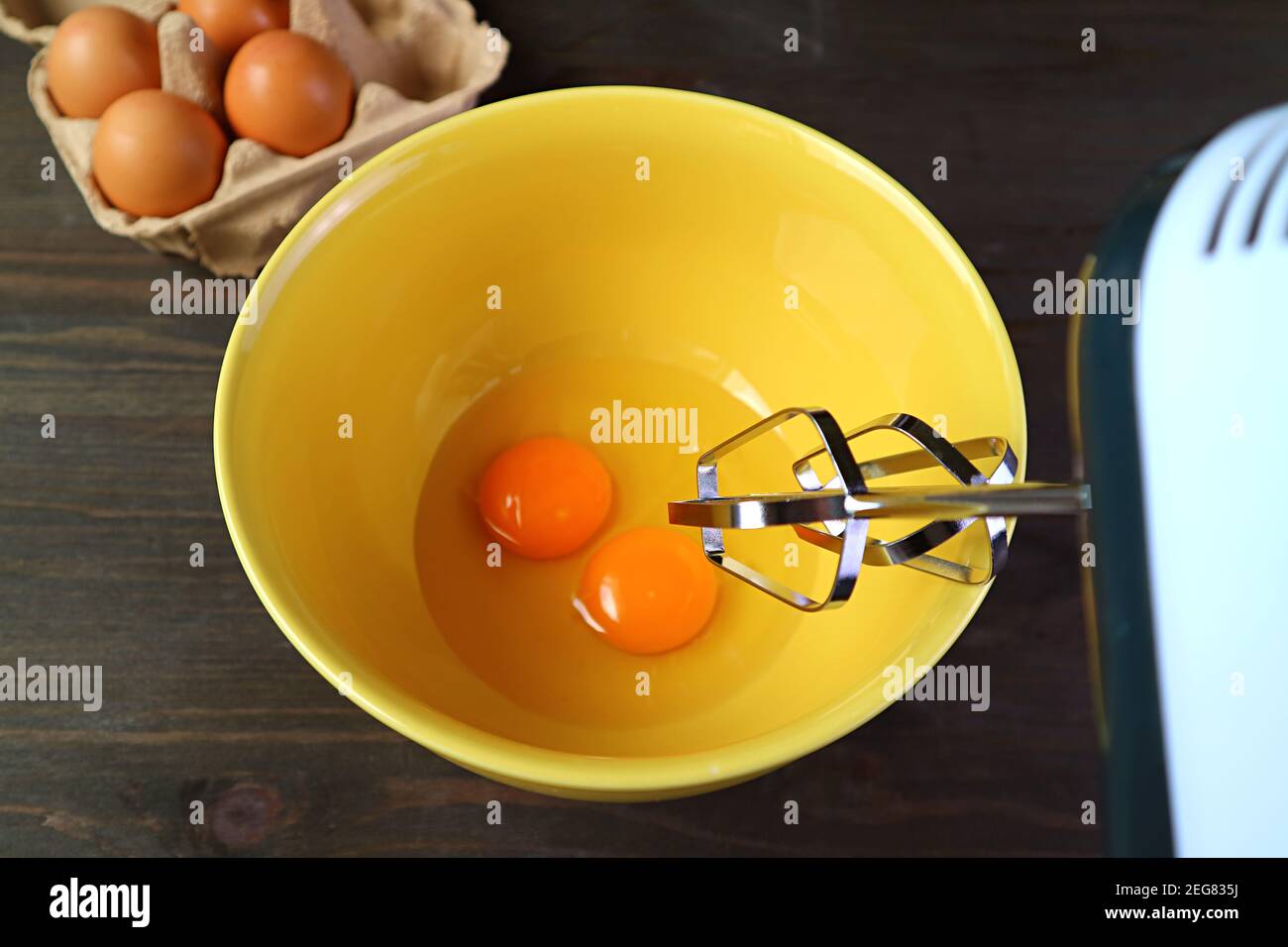 Primer plano del batidor eléctrico del huevo que va a batir un par de Huevos  crudos en el cuenco de mezcla Fotografía de stock - Alamy