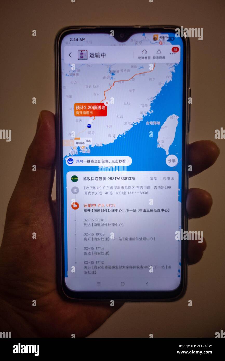 La pantalla del teléfono muestra la actualización logística de Taobao en tiempo real a medida que el icono del camión se desplaza por el mapa de China hasta el destino de la entrega, la información de seguimiento en chino Foto de stock