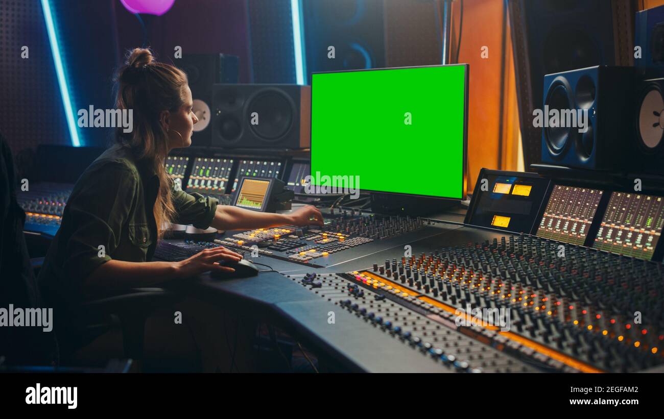 Retrato de una elegante productora de ingeniero de audio trabajando en Music Record Studio, utiliza pantalla de ordenador verde, placa mezcladora, escritorio de control a. Foto de stock