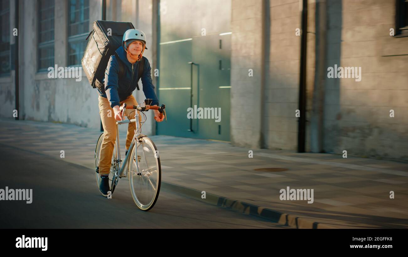 Happy Food Delivery Courier con mochila térmica se lleva una bicicleta en  el camino para entregar pedidos para clientes y clientes. Día soleado en la  ciudad moderna Fotografía de stock - Alamy