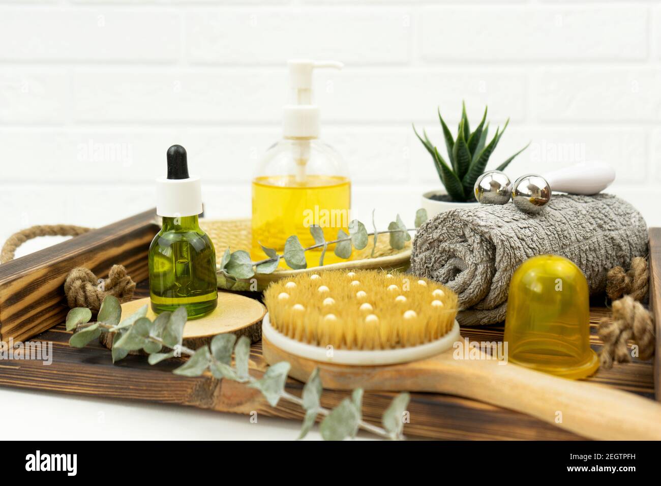 Aceite para la cara y rodillo para la cara, cepillo para masaje seco y una  toalla de algodón se encuentran en una bandeja de madera Fotografía de  stock - Alamy