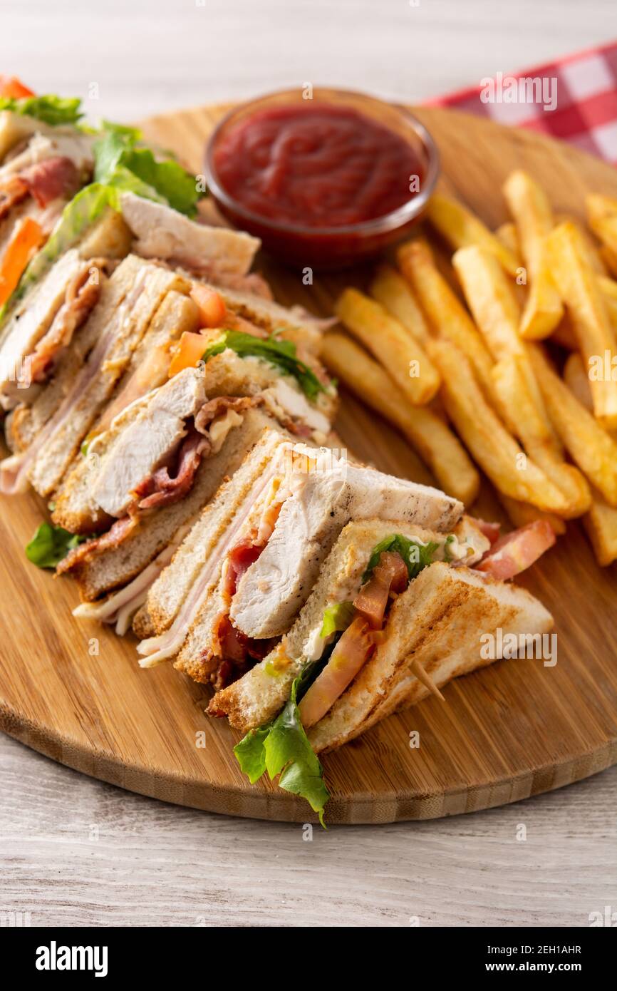 Club sandwich y patatas fritas sobre mesa de madera Foto de stock