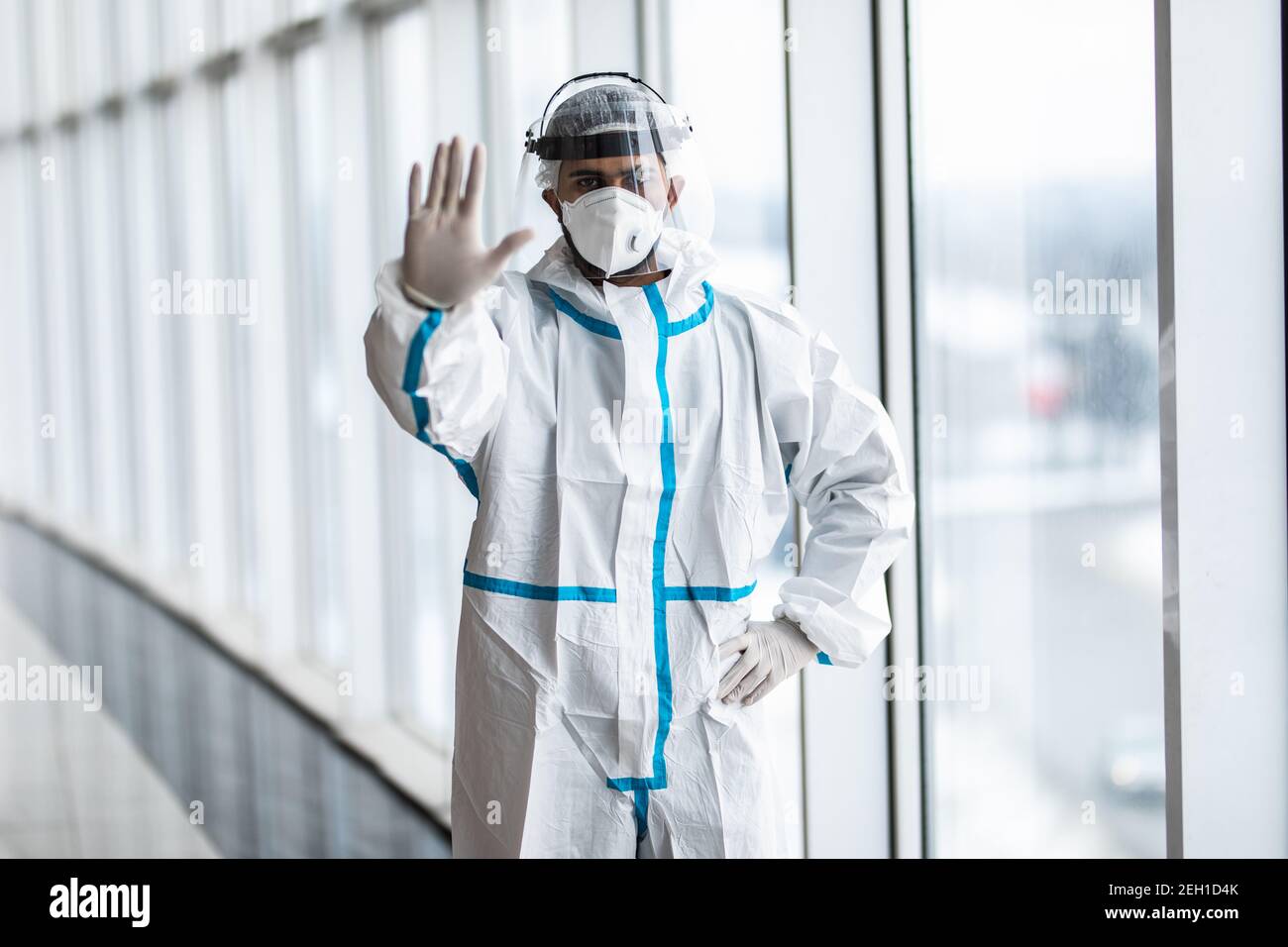 Hombre médico en un traje blanco de hazmat y máscara gestual pare con la  mano en el hospital Fotografía de stock - Alamy