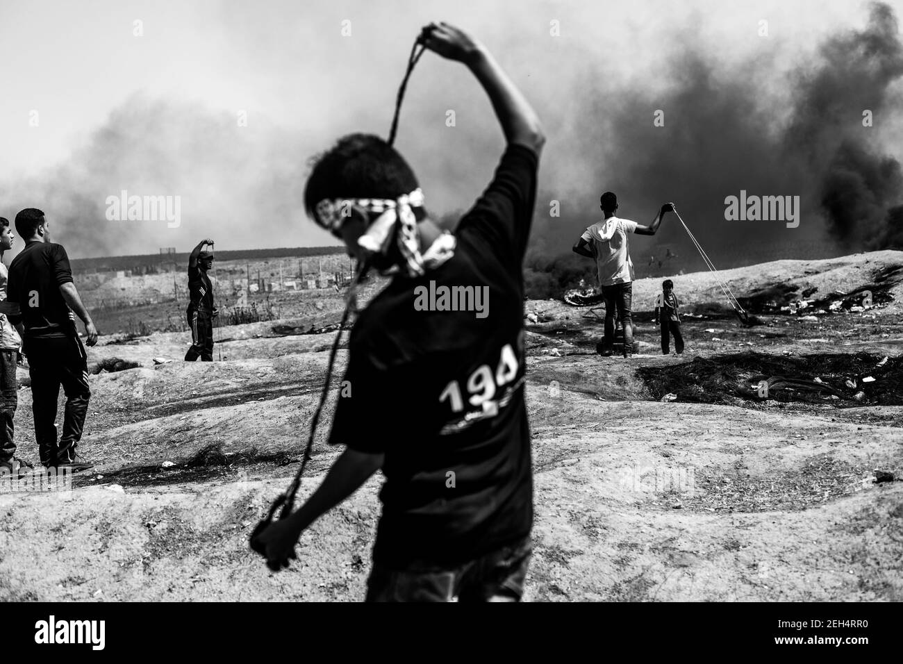 Un manifestante palestino utiliza un disparo de bala para lanzar piedras contra las fuerzas israelíes durante las manifestaciones en la frontera oriental de la ciudad de Gaza con Israel. Las tensiones son altas a lo largo de la frontera entre Gaza e Israel después de más de un mes de protestas masivas semanales cerca de la barrera que mató a 50 manifestantes palestinos e hirió a más de 1,700 por el fuego militar israelí. Los líderes de Hamas en Gaza han prometido que las marchas continuarán hasta que se levante el bloqueo israelí del territorio, que dura diez años. Las protestas también se esperan el 14 y 15 de mayo, el día en que los palestinos marcarán Yawm an-Nakba o 'día de Disaste Foto de stock