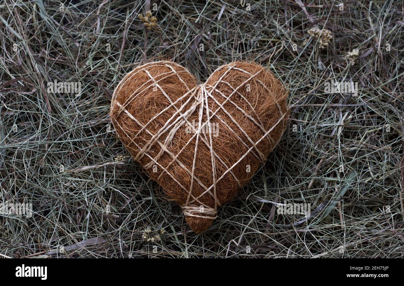 Paja decorativa hecha a mano y corazón de paja, sobre fondo de madera