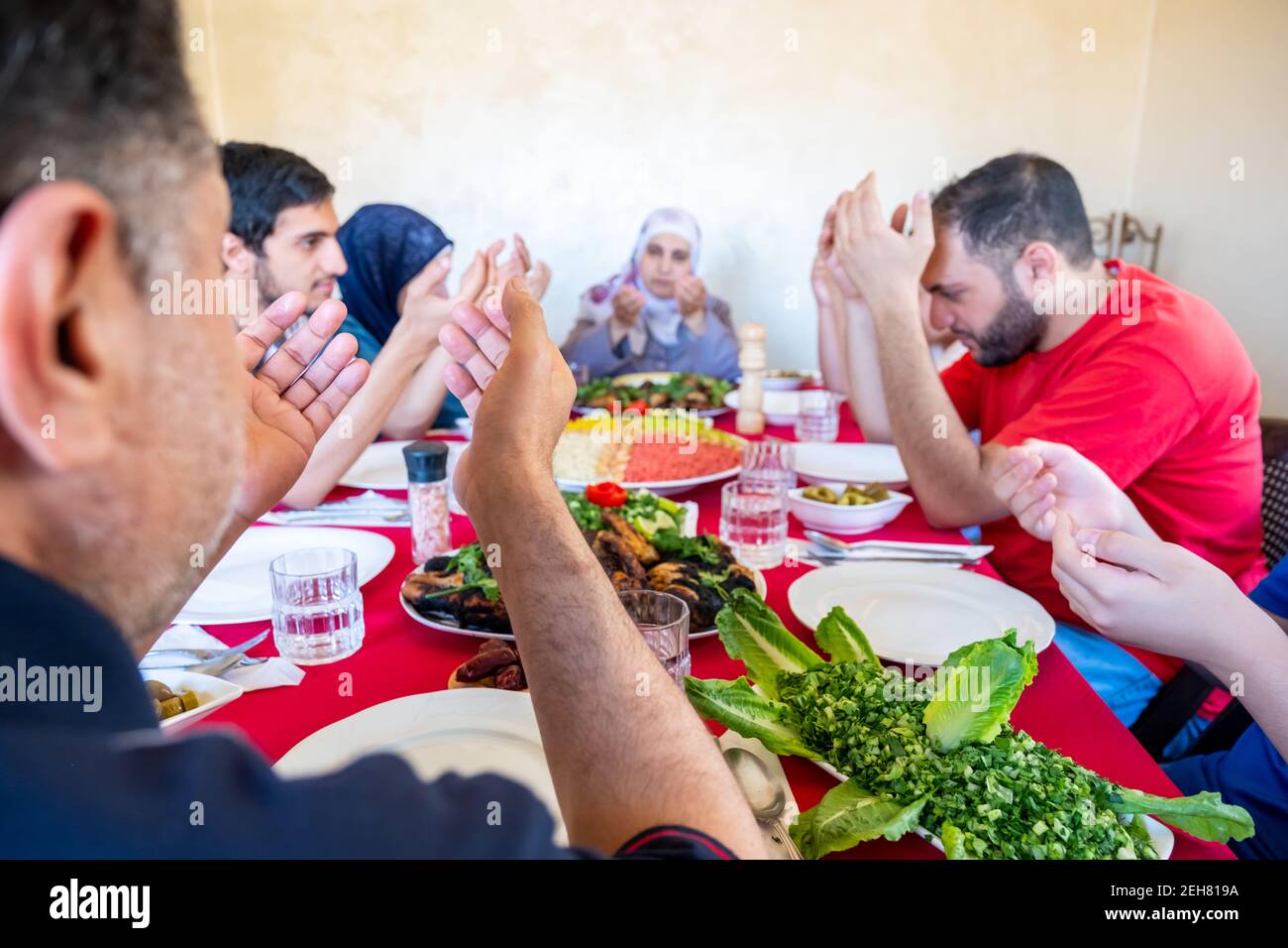 Familia árabe musulmana orando por dios antes de comer iftar Fotografía