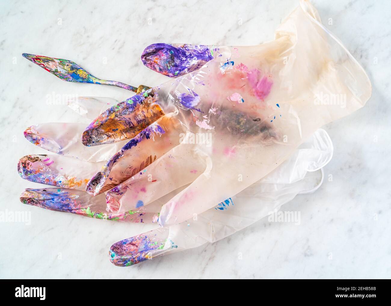 Los guantes de látex transparente de un artista cubiertos de salpicaduras de pintura. Foto de stock