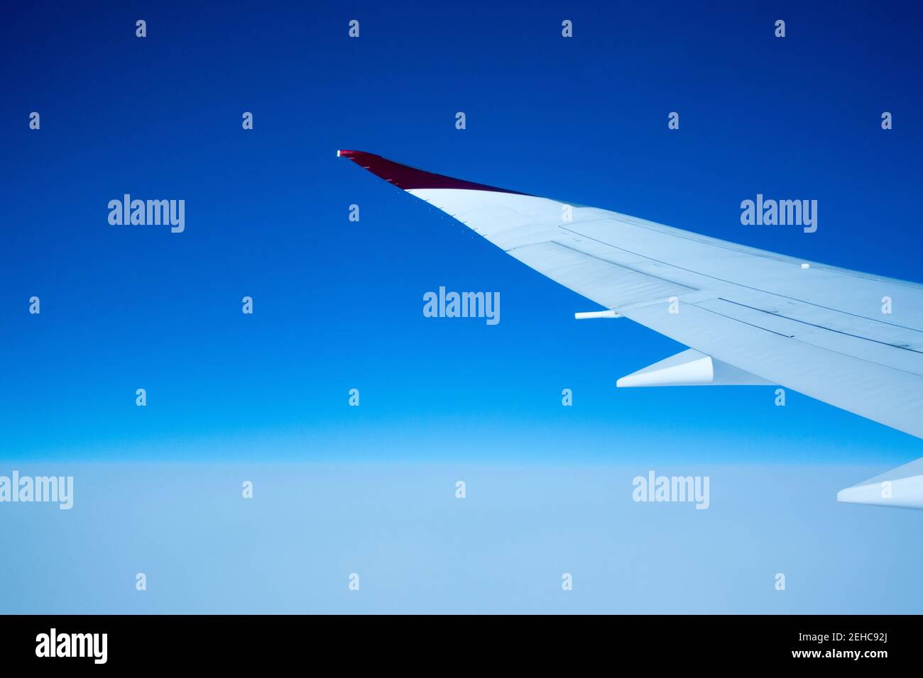 Concepto de viaje aéreo con ala de avión que se extiende en un blanco y el cielo azul Foto de stock