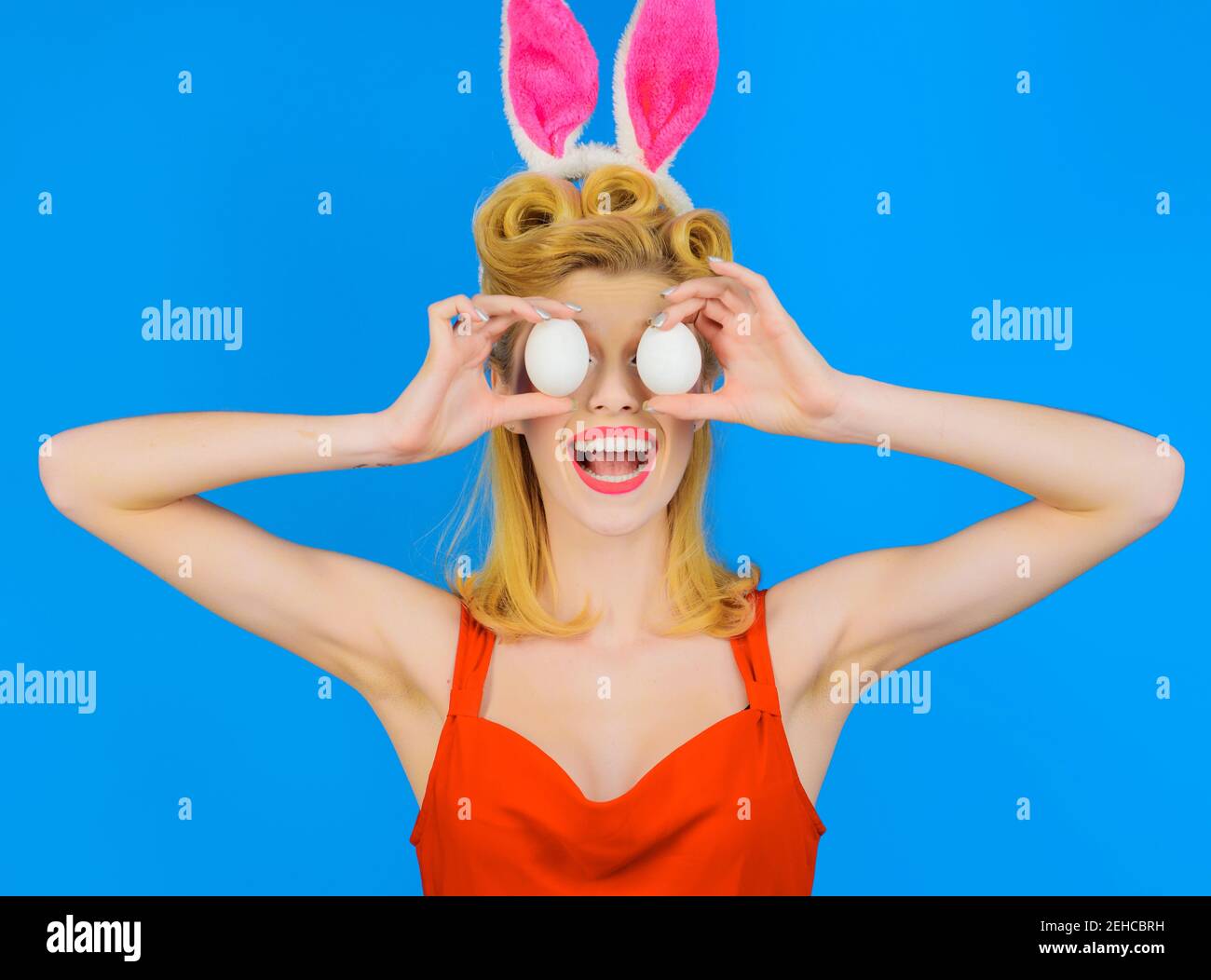 Chica conejita con huevos blancos. Felices Pascuas. Mujer divertida en orejas de conejo. Adornar el huevo. Foto de stock