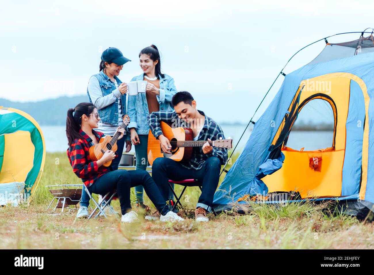 Grupo de amigos acampando y están sentados tocando la guitarra. Concepto de  campamento y guitarra musical Fotografía de stock - Alamy