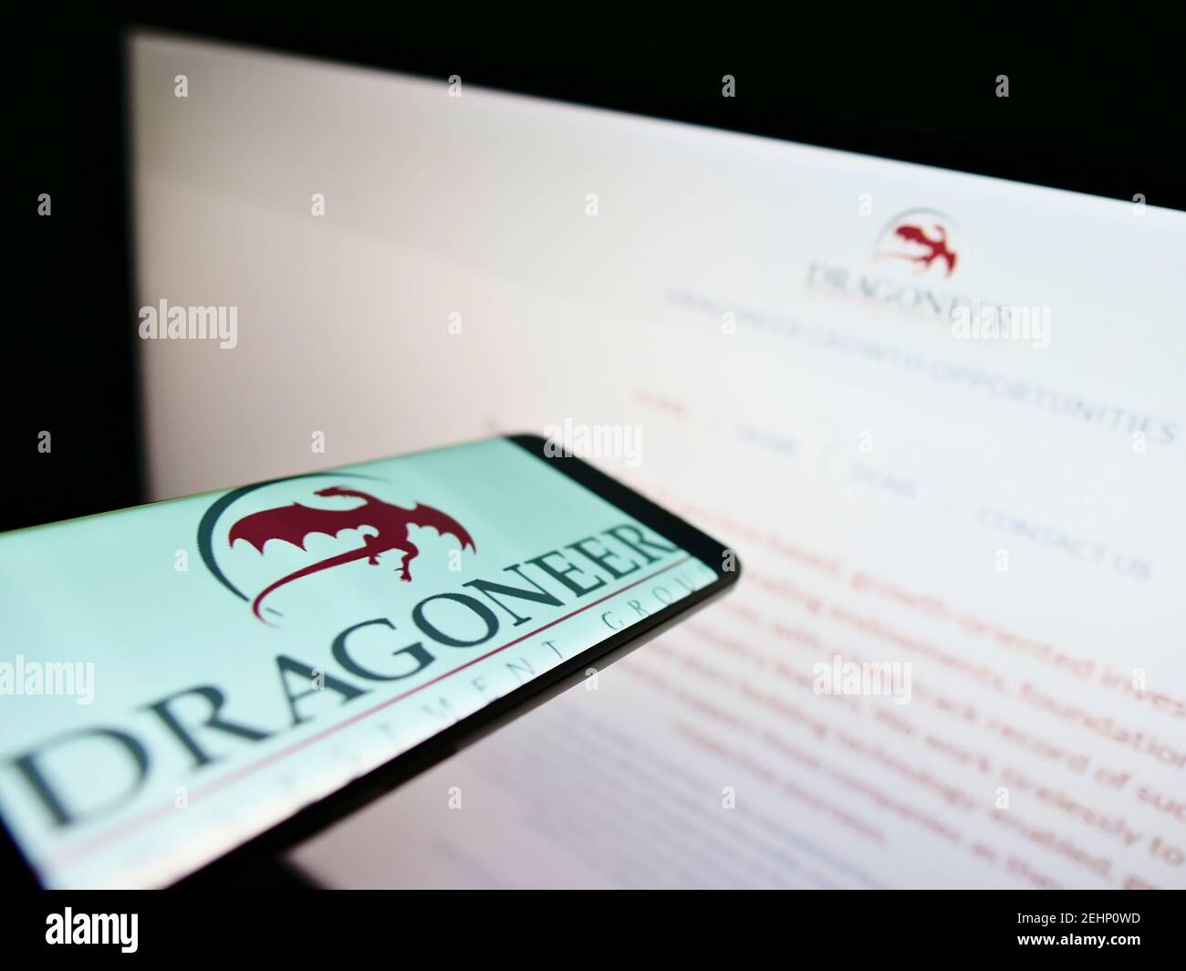 Teléfono móvil con el logotipo de la empresa del inversor americano Dragoneer Investment Group en la pantalla frente al sitio web. Enfoque en el centro de la pantalla del teléfono. Foto de stock