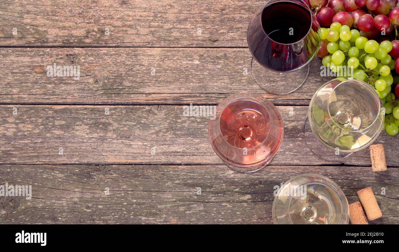 Variedad de vinos y bocadillos. Diferentes tipos de uvas. Ingredientes frescos sobre fondo de madera. Vista superior Foto de stock