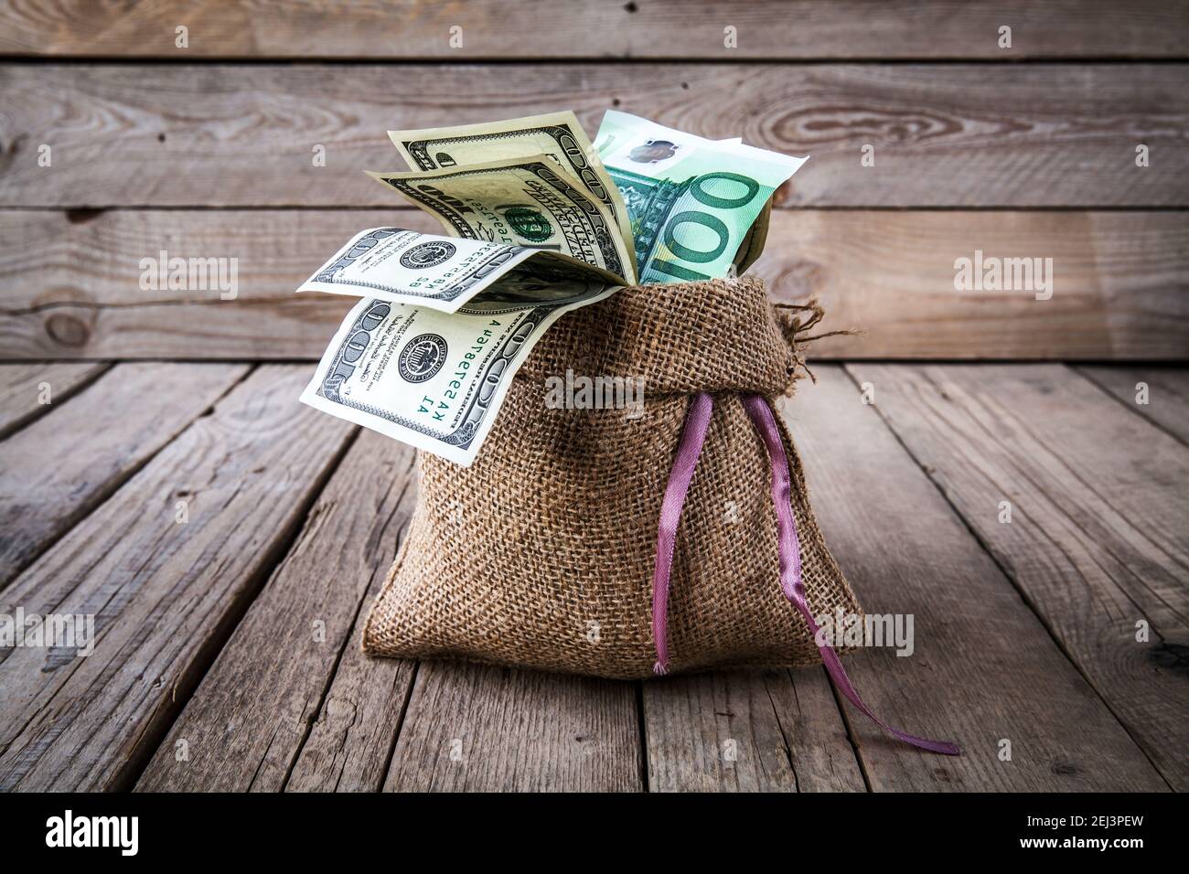 dinero en tela de sackcloth y monedas scattere y d en una madera antecedentes y. Foto de stock