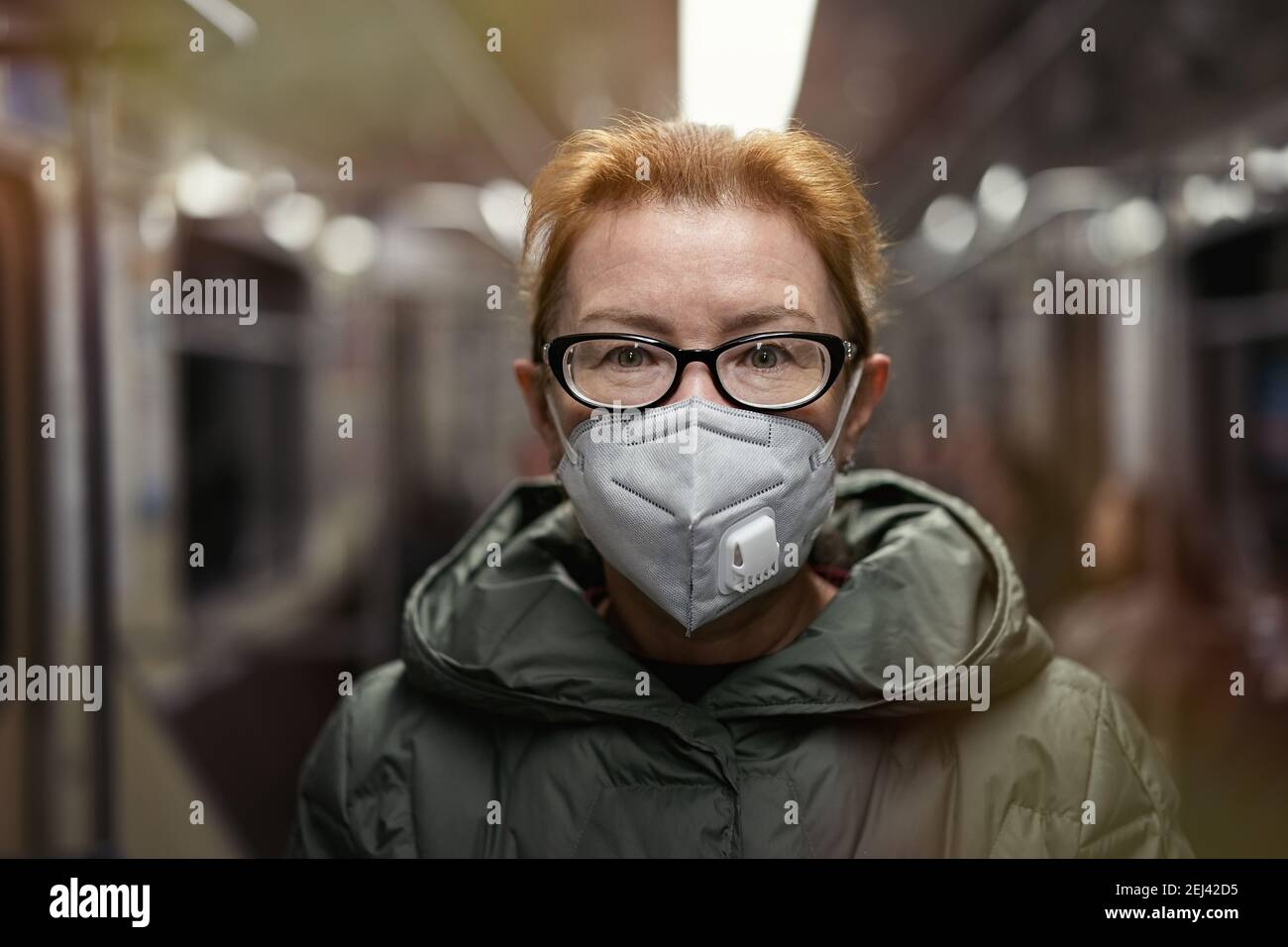 Retrato mujer madura en máscara de respiración viajando en tren subterráneo. Concepto de nueva realidad vital durante la pandemia de COVID 19 Foto de stock