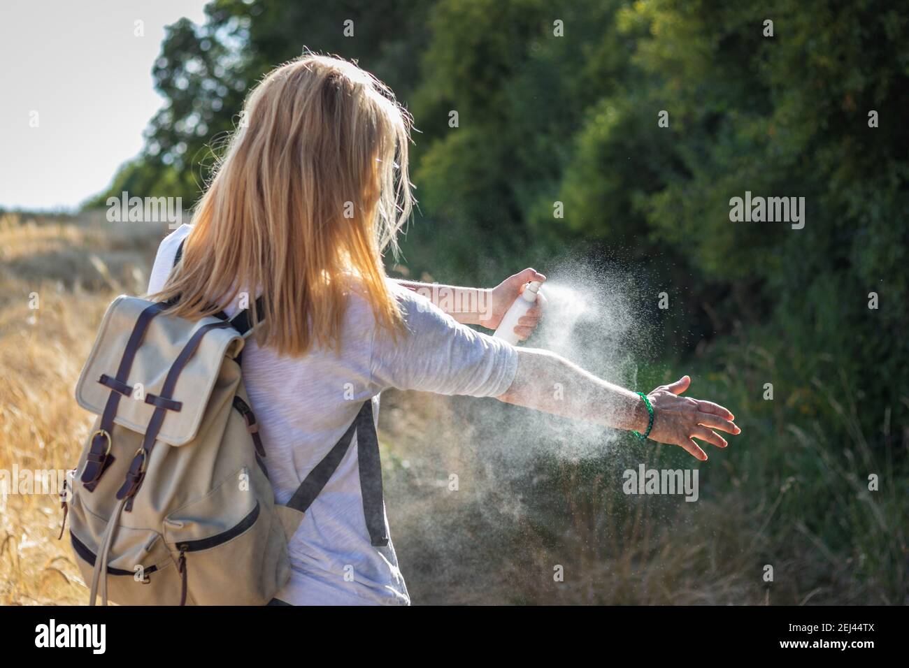 Mujer turista aplicando repelente de mosquitos a mano durante la caminata en la naturaleza. Repelente de insectos. Protección de la piel contra garrapatas y otros insectos. Foto de stock