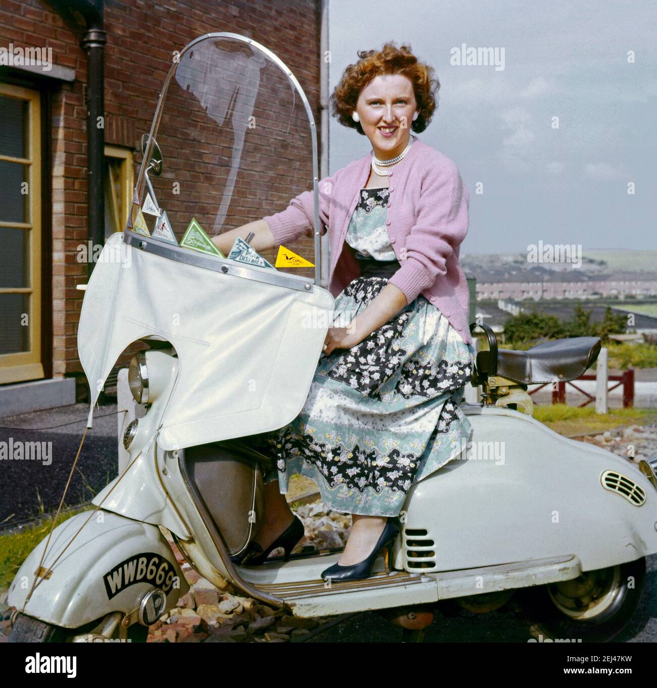 Mujer joven en scooter c.1960. Los lugares que el scooter visitado se muestran como pennants en el parabrisas - una fotografía clásica de justo de la época en que