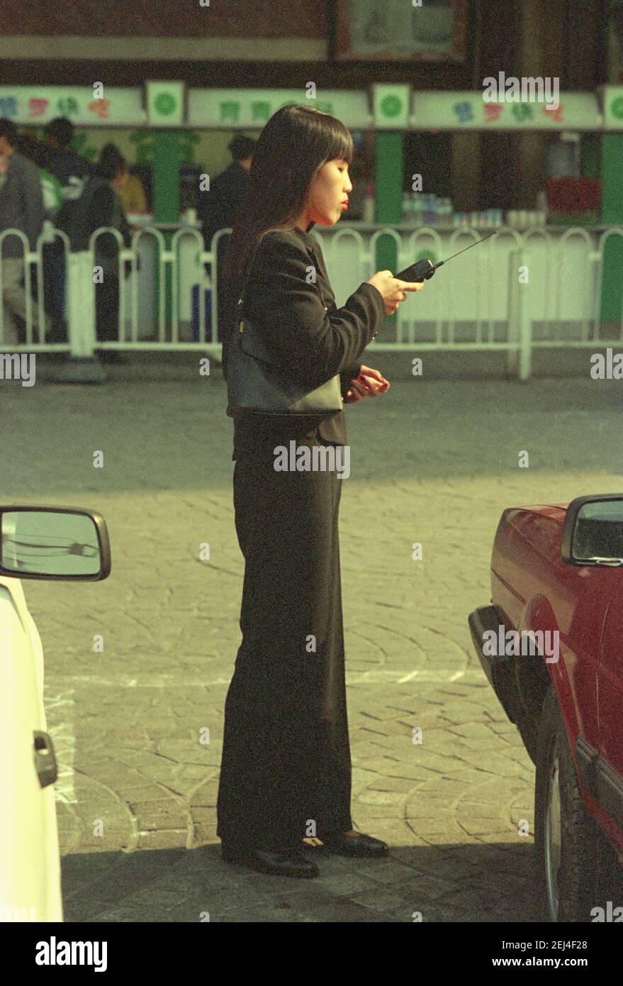 La señora China utiliza un teléfono celular Motorola en Beijing, China en 1998. Foto de stock