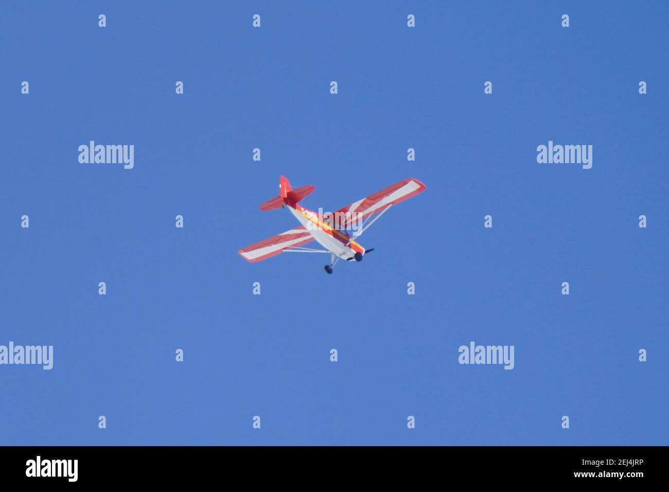 Pequeño avión privado que vuela contra el brillante cielo azul del invierno Foto de stock