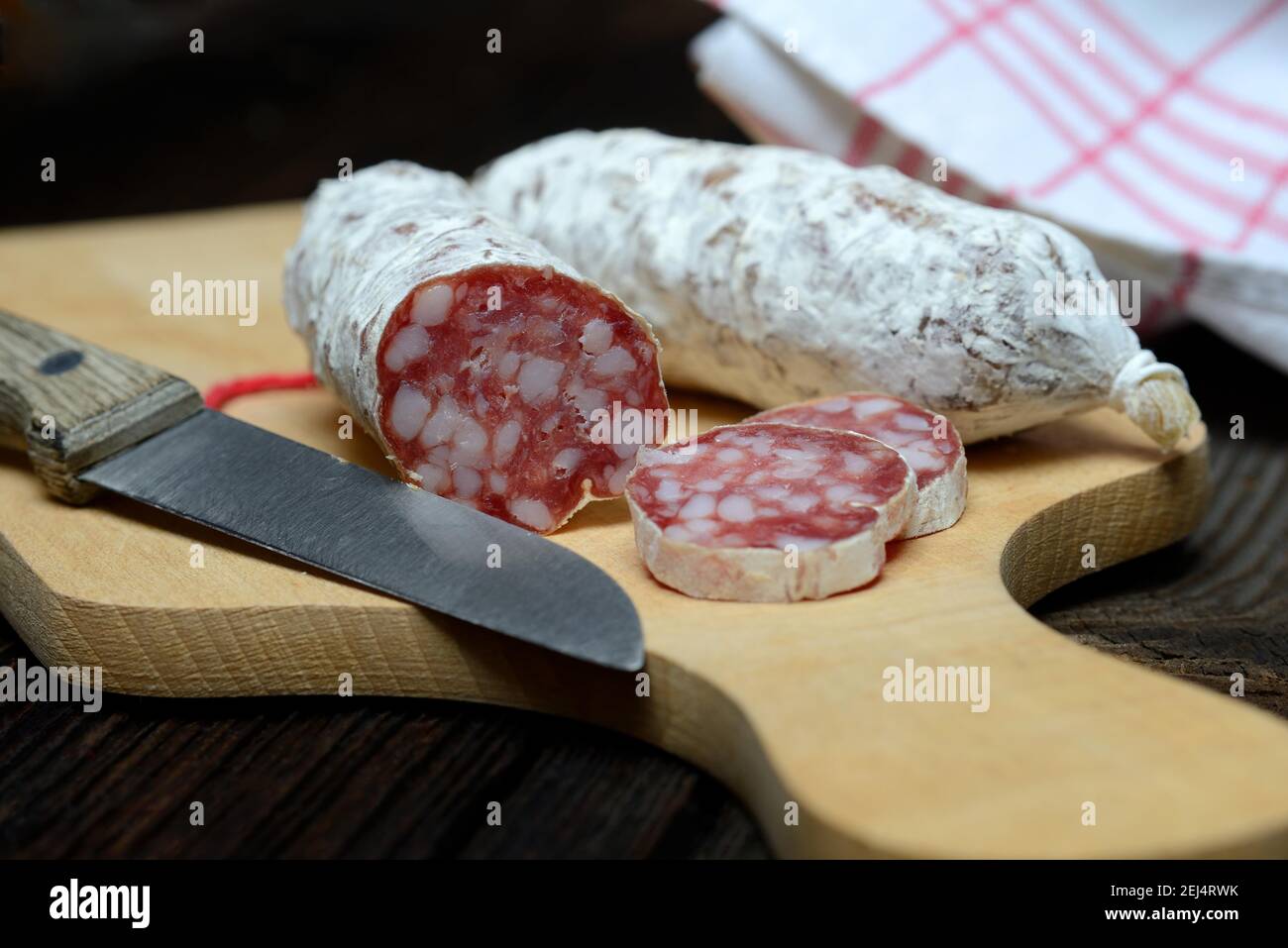 Salami, salametti con cuchillo de cocina, sobre tabla de madera, Dauerwurst, Dauerwuerste Foto de stock