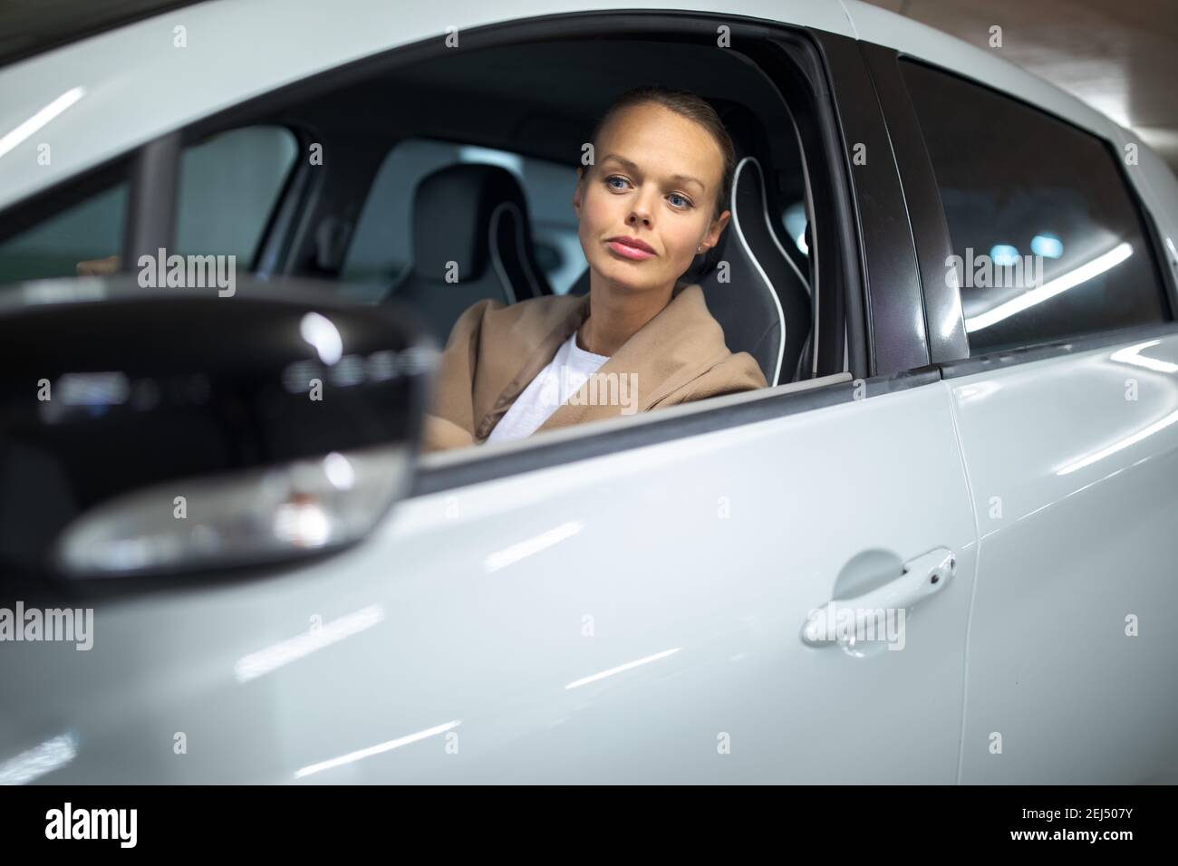 Estacionamiento subterráneo/garaje (DOF poco profundo; imagen en tonos de color) - mujer joven con su coche en el estacionamiento subterráneo Foto de stock