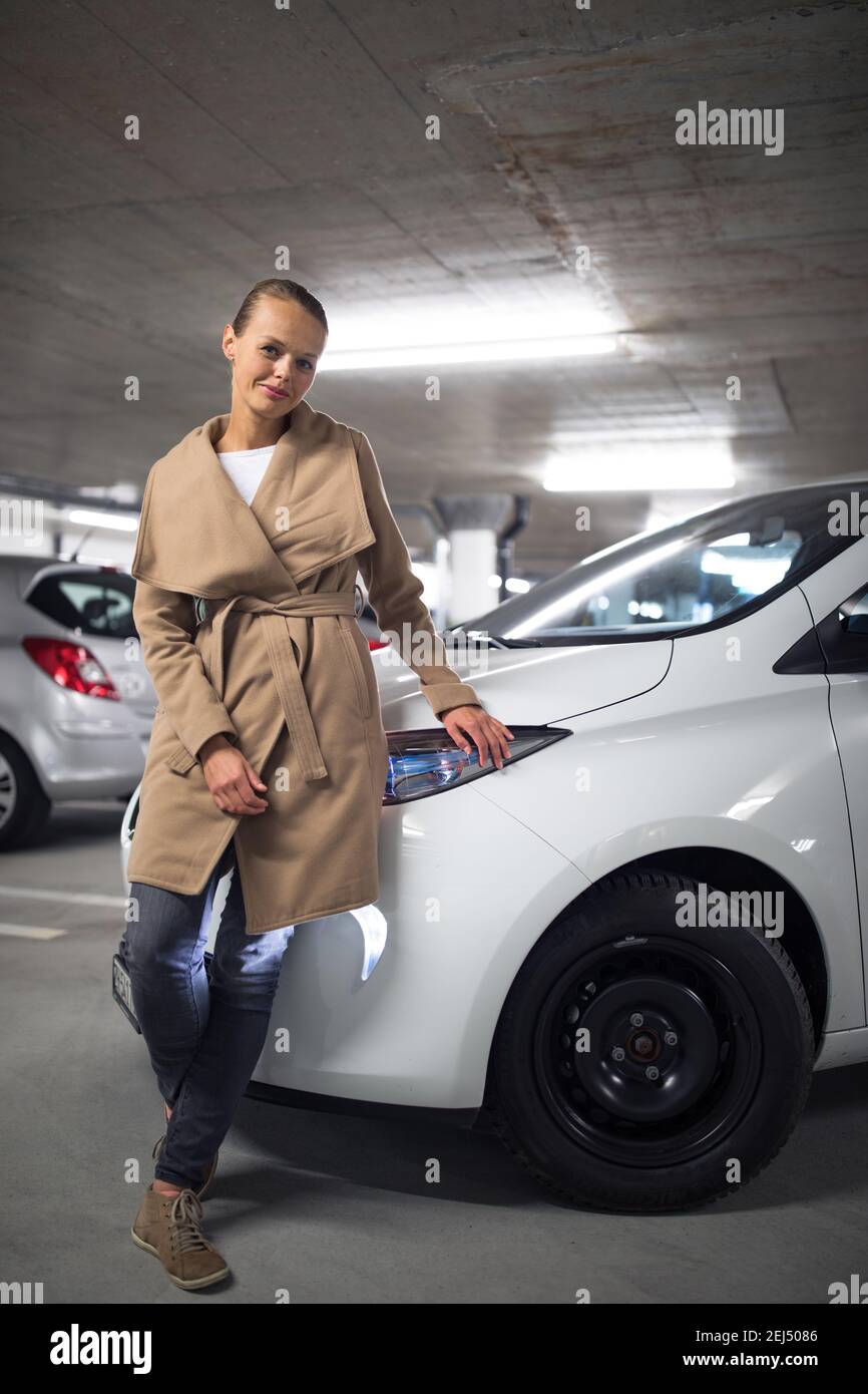 Estacionamiento subterráneo/garaje (DOF poco profundo; imagen en tonos de color) - mujer joven con su coche en el estacionamiento subterráneo Foto de stock