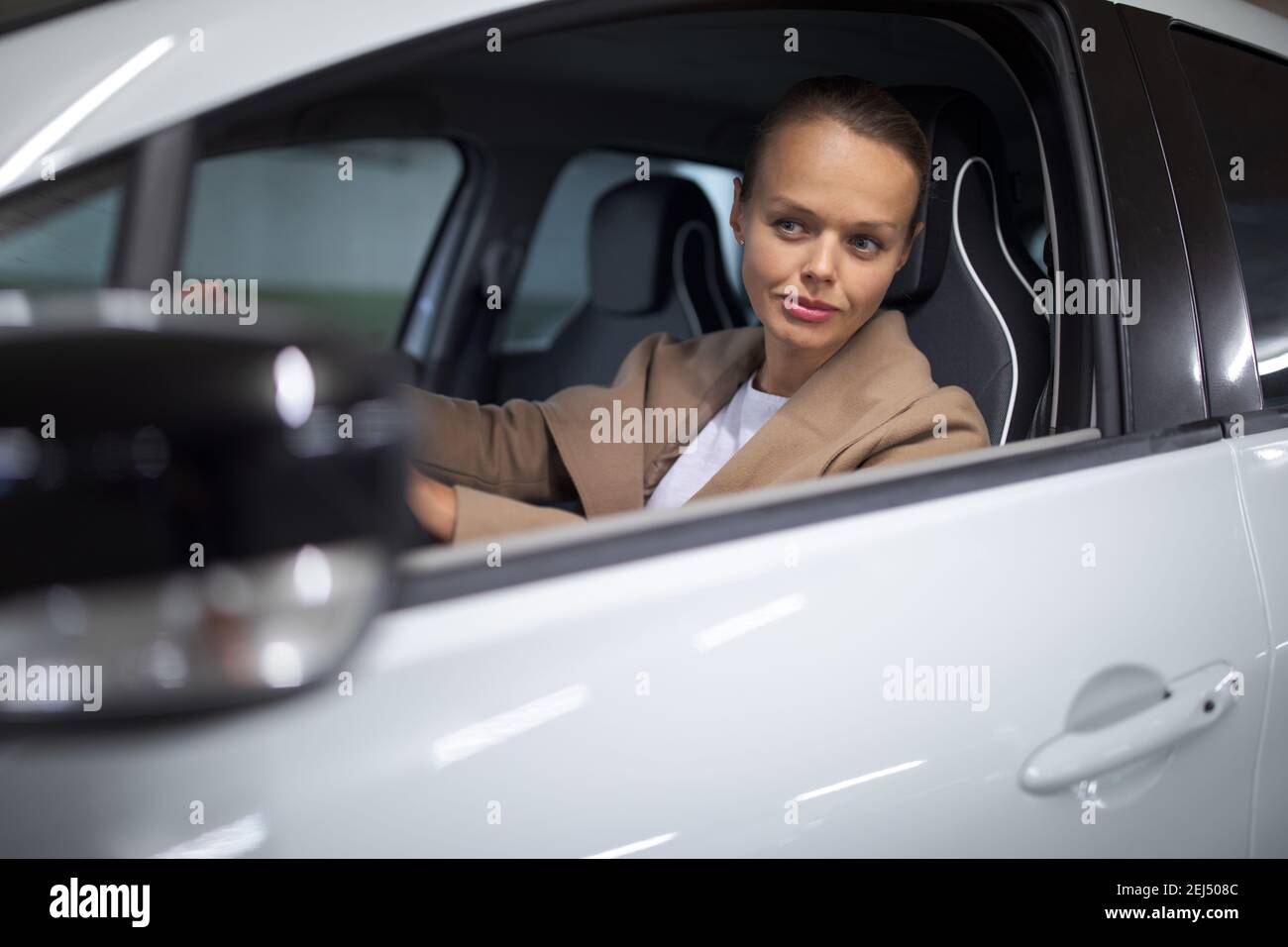 Estacionamiento subterráneo/garaje (DOF poco profundo; imagen en tonos de color) - mujer joven con su coche en el estacionamiento subterráneo Foto de stock