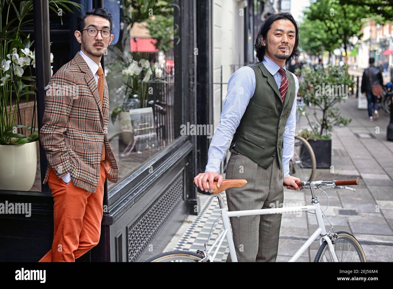 Dos jóvenes asiáticos saliendo de la tienda con bicicleta en Londres, Reino Unido Foto de stock