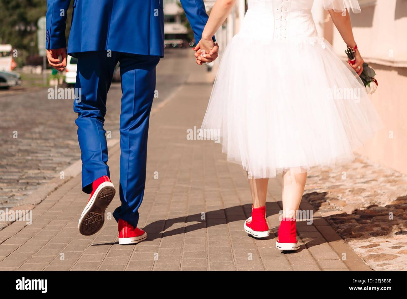 y en zapatillas rojas están por la calle. Concepto de boda Hipster Fotografía stock - Alamy