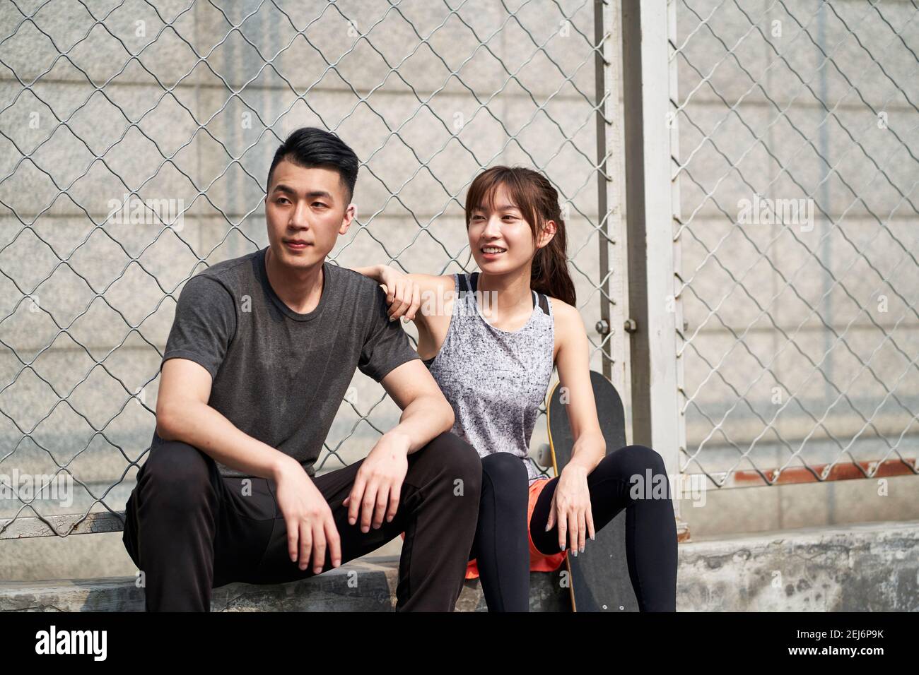 joven asiático adulto hombre y mujer descansando al aire libre después del ejercicio Foto de stock